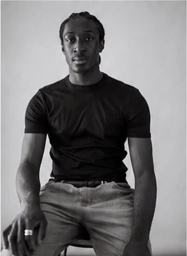 Brian N seated studio portrait in a black t-shirt