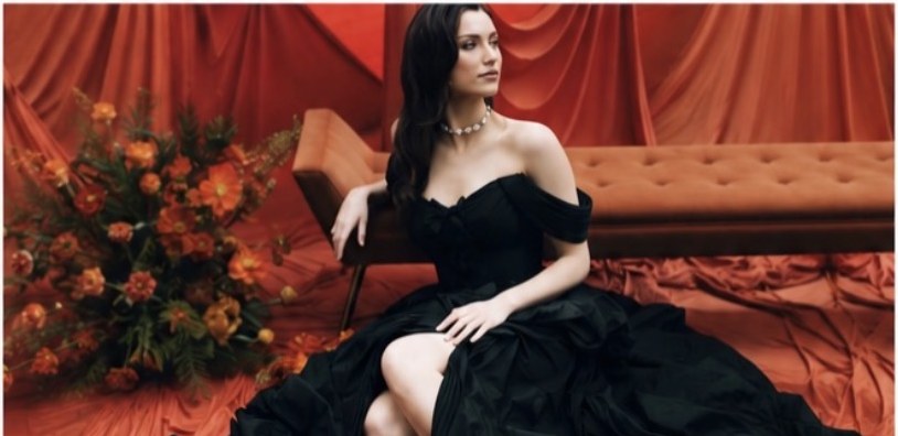 Abigail M seated editorial portrait in a black gown on a red set