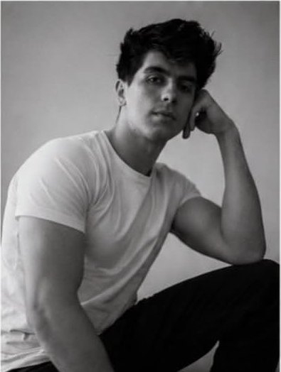 Adam C seated portrait in a white t-shirt