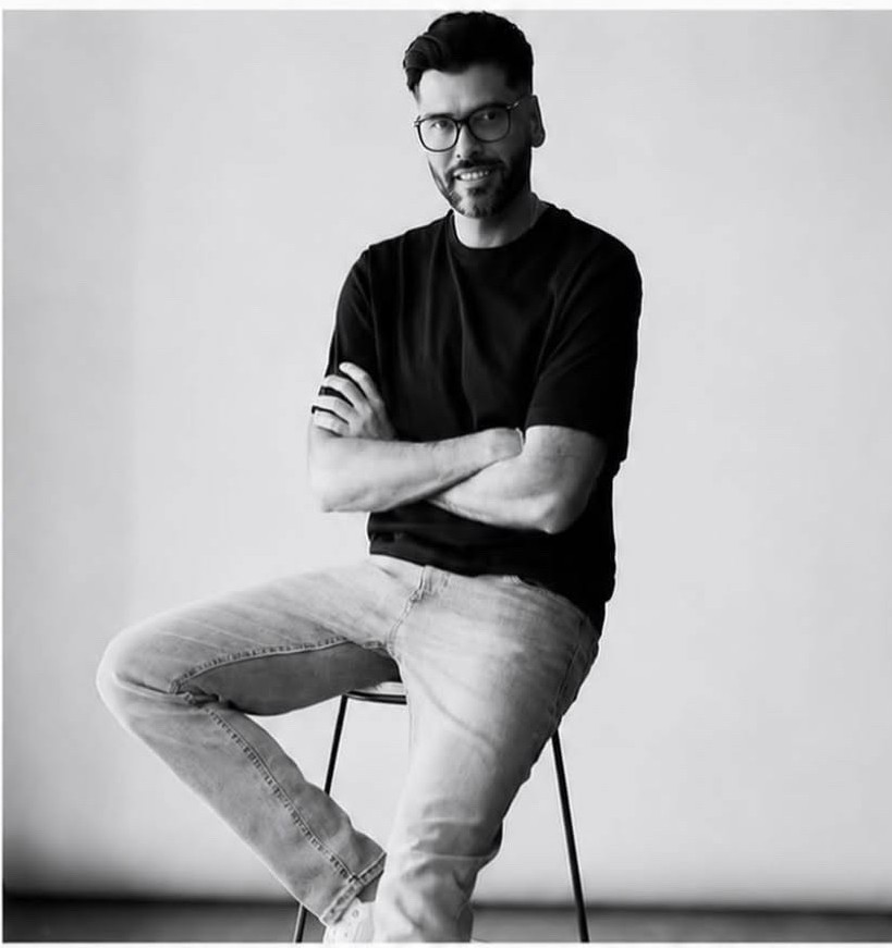 Brendan C, male model, seated studio portrait in a black t-shirt and jeans
